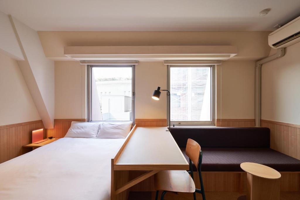 1 dormitorio con 1 cama, banco y 2 ventanas en ホテルレジデンス大橋会館 by Re-rent Residence en Tokio