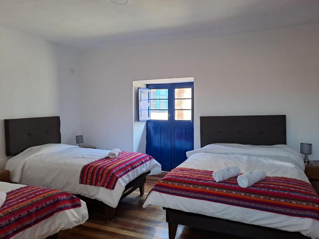1 dormitorio con 2 camas y puerta azul en Marina's House Cusco Centro, en Cusco