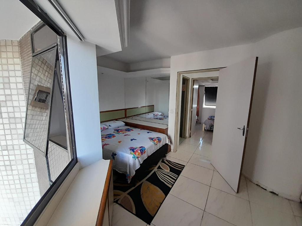 a small bedroom with a bed and a hallway at Apartamento dúplex em frente ao mar de Pajuçara in Maceió