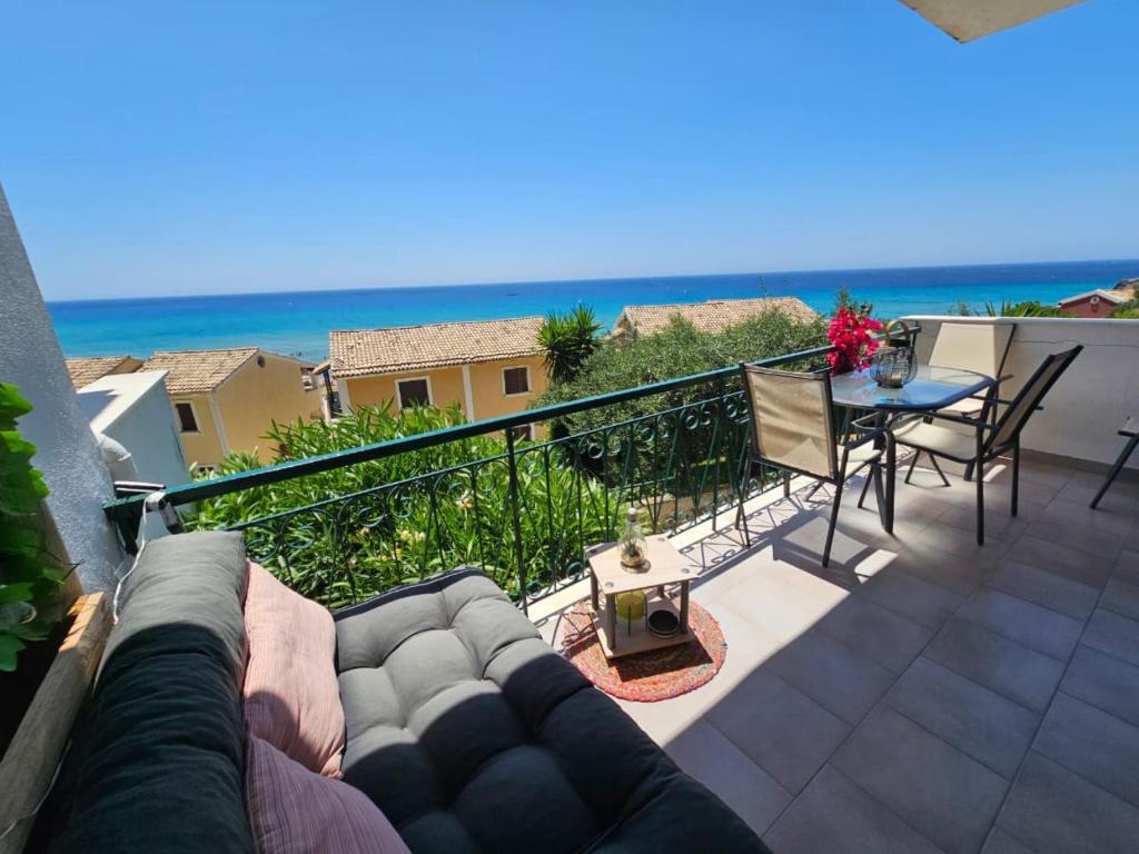 uma varanda com um sofá e uma mesa e o oceano em Standart Apartments , Glyfada Beach em Glyfada