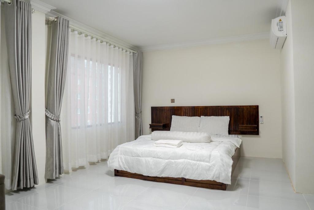 a white bedroom with a bed and a large window at Empire House, Phnom Penh in Phnom Penh