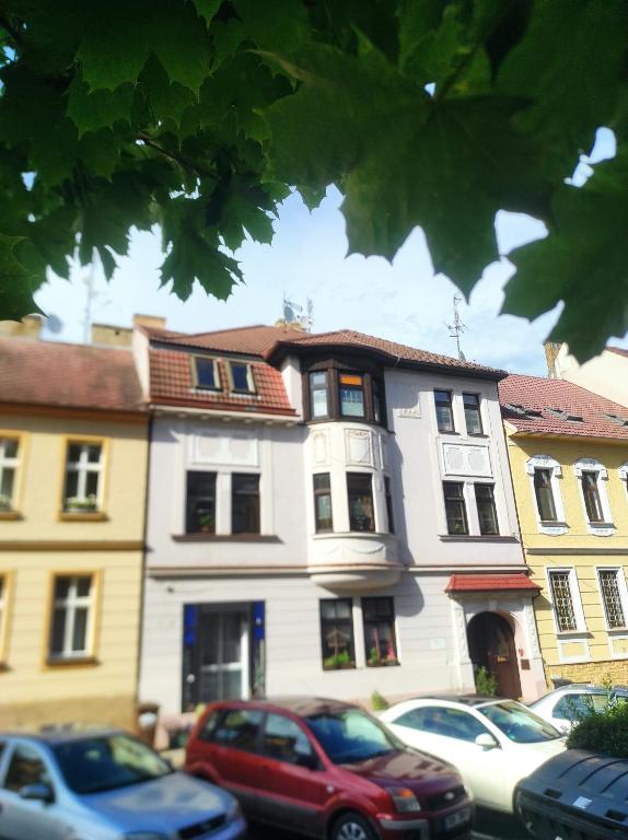 biały budynek z zaparkowanymi przed nim samochodami w obiekcie Pension Relax w Litomierzycych