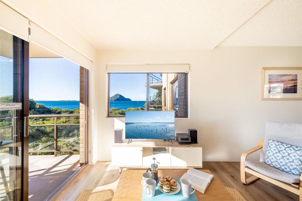 a living room with a tv and a large window at Intrepid, 15 3 Intrepid Close - right on the beachfront and WiFi in Shoal Bay