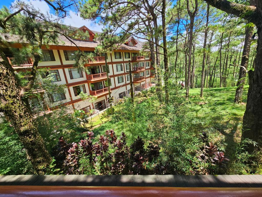 an exterior view of a building in the woods at The Forest Lodge at Camp John Hay with balcony and parking privately owned unit 272 in Baguio