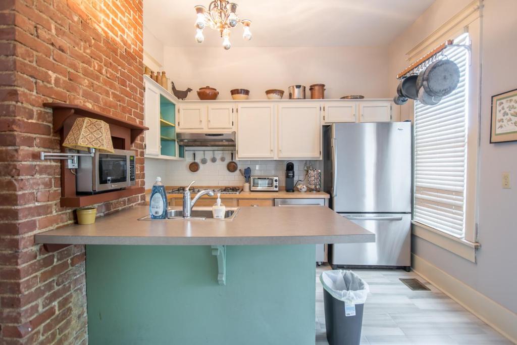 a kitchen with white cabinets and a brick wall at Southern Sophistication and Charm in the Heart of Cooper Young in Memphis