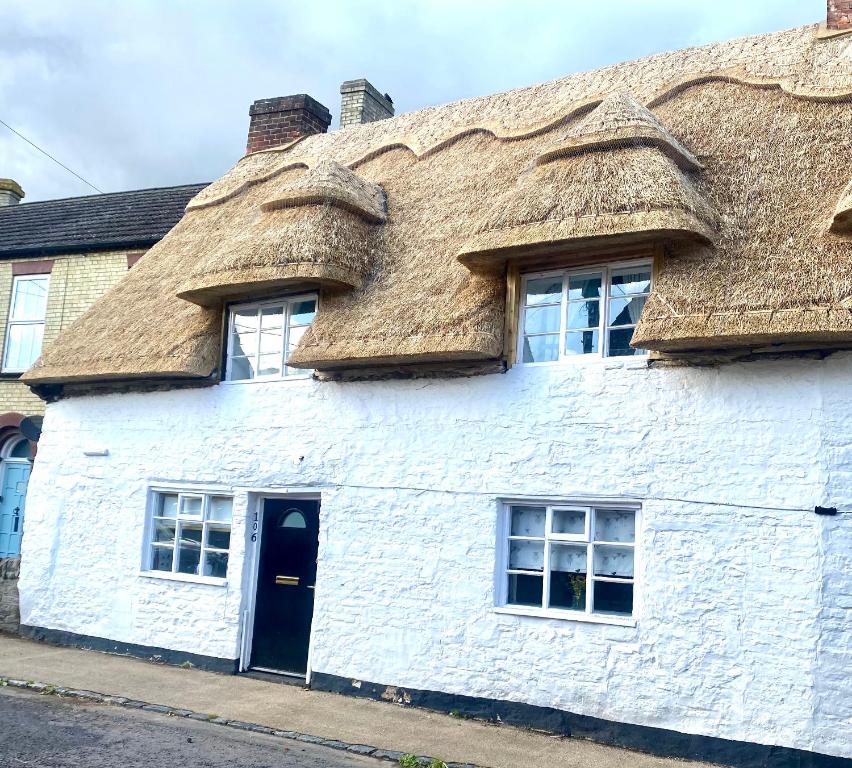 um edifício branco com telhado de palha em Two Bedroom Cosy Character Cottage Sleeps 4 