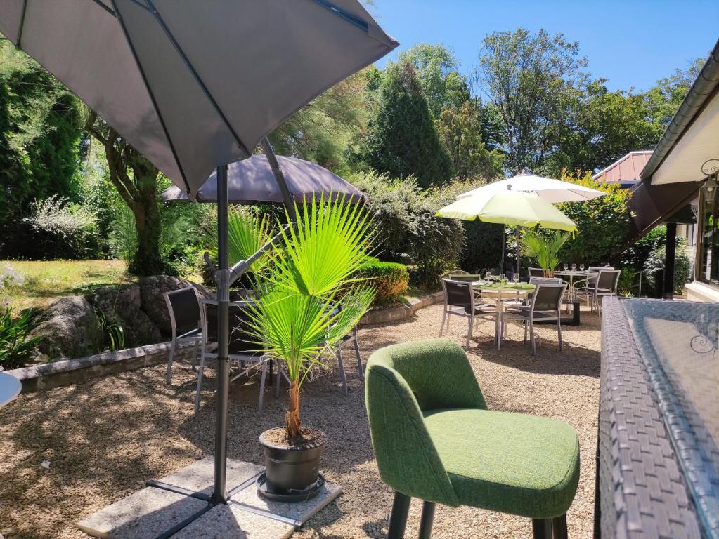 une terrasse avec une table, des chaises et un parasol dans l'établissement Hôtel Be Guest Limoges Sud ex Black & Green, à Limoges