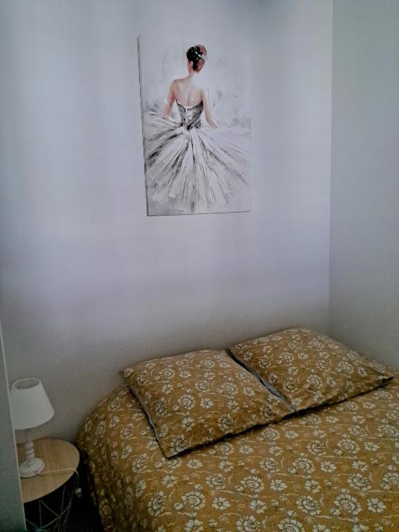 a bed with a picture of a woman on the wall at La Maison du Bonheur - Logement entier de 39 m2 in Bourg-en-Bresse