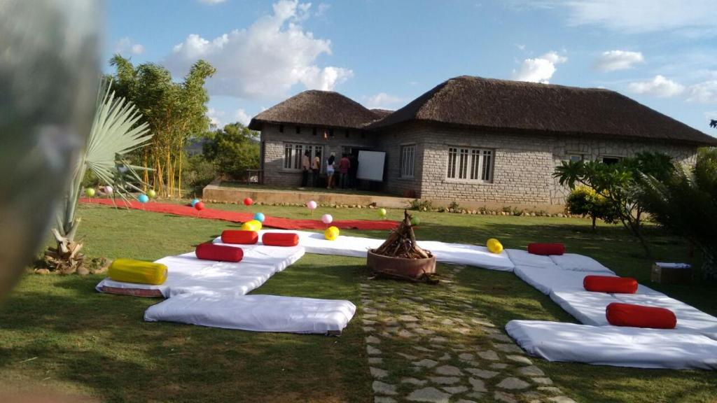 a group of pillows on the grass in front of a house at Vamoose Hampi Homestay Otters Island in Hampi