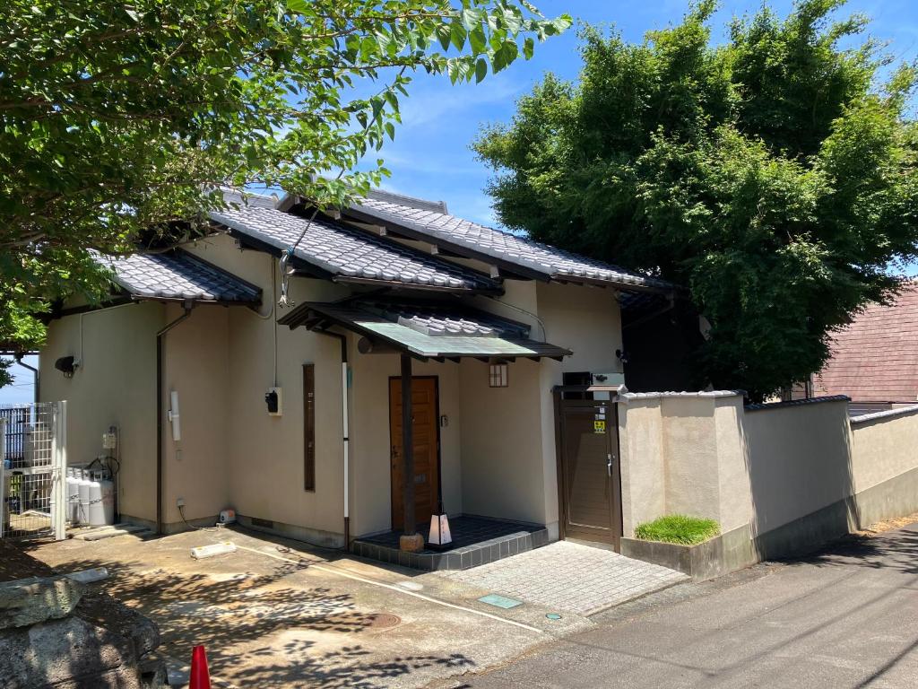 a small white house with an awning on a street at 熱海の海が一望できる温泉付貸別荘 満月あじろ mitsukiajiro in Atami