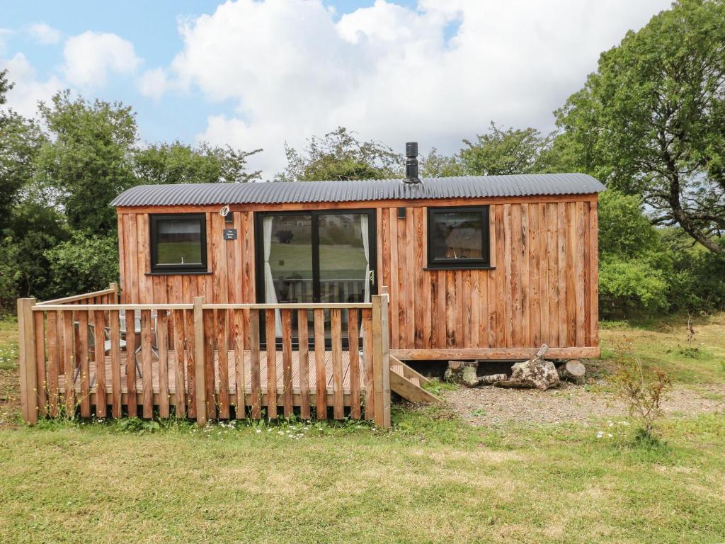 a wooden cabin in a field with a fence at The Queen Bee in Pembroke