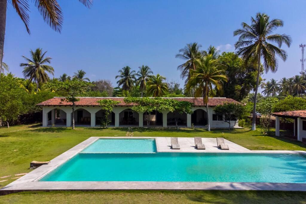 a swimming pool in front of a house with palm trees at Casablanca - Frente al Mar - 16 personas - 5 hab in Acajutla