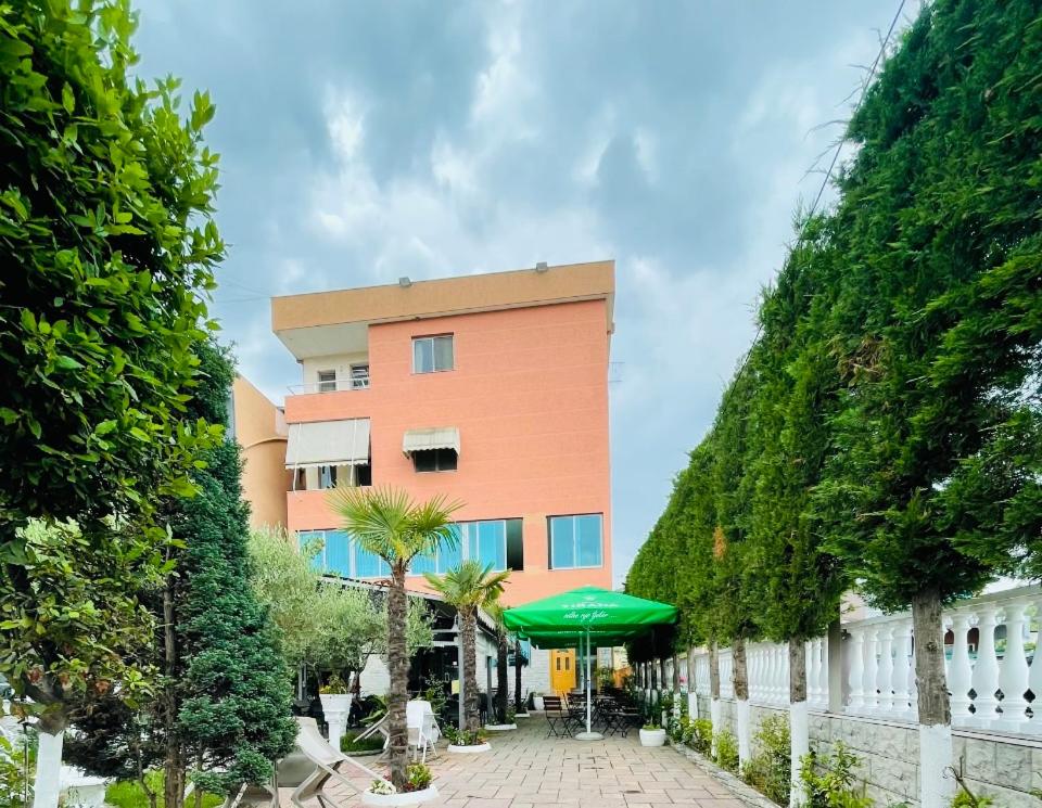 un edificio con una sombrilla verde delante de él en Bajovah Apartments & Restaurant, en Tirana