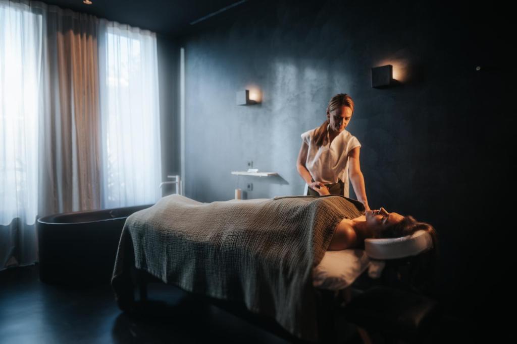 a woman cutting a mans head on a bed at Maslina Resort in Stari Grad