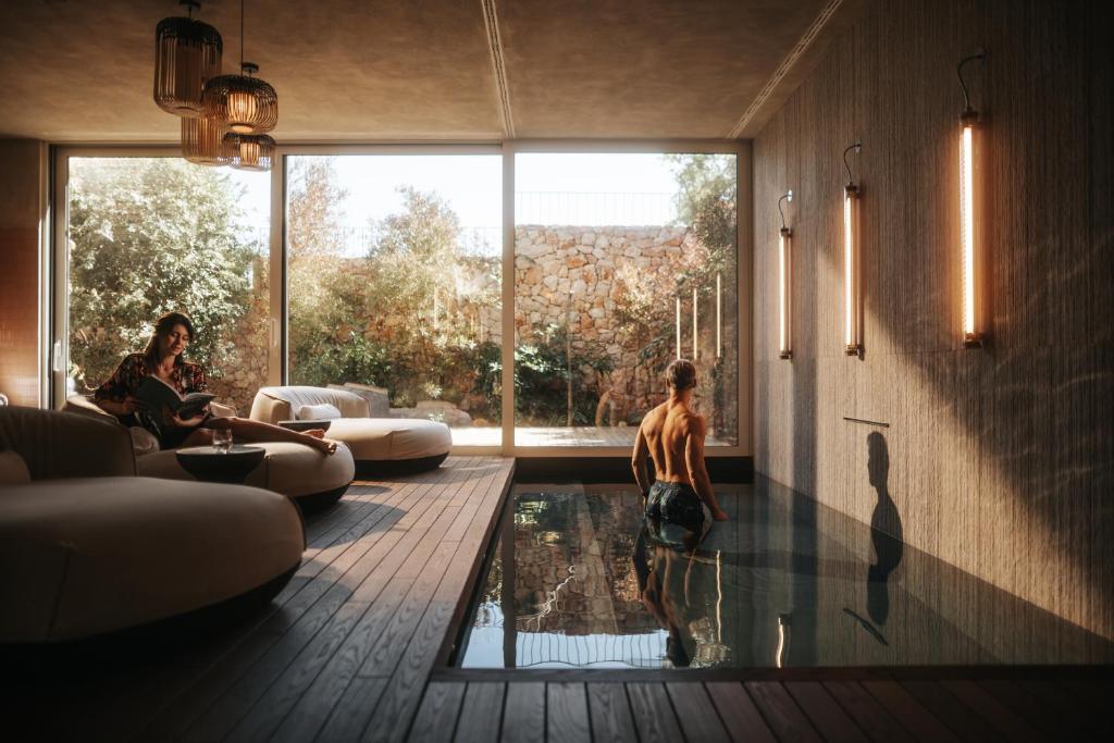 a man standing in a swimming pool in a living room at Maslina Resort in Stari Grad