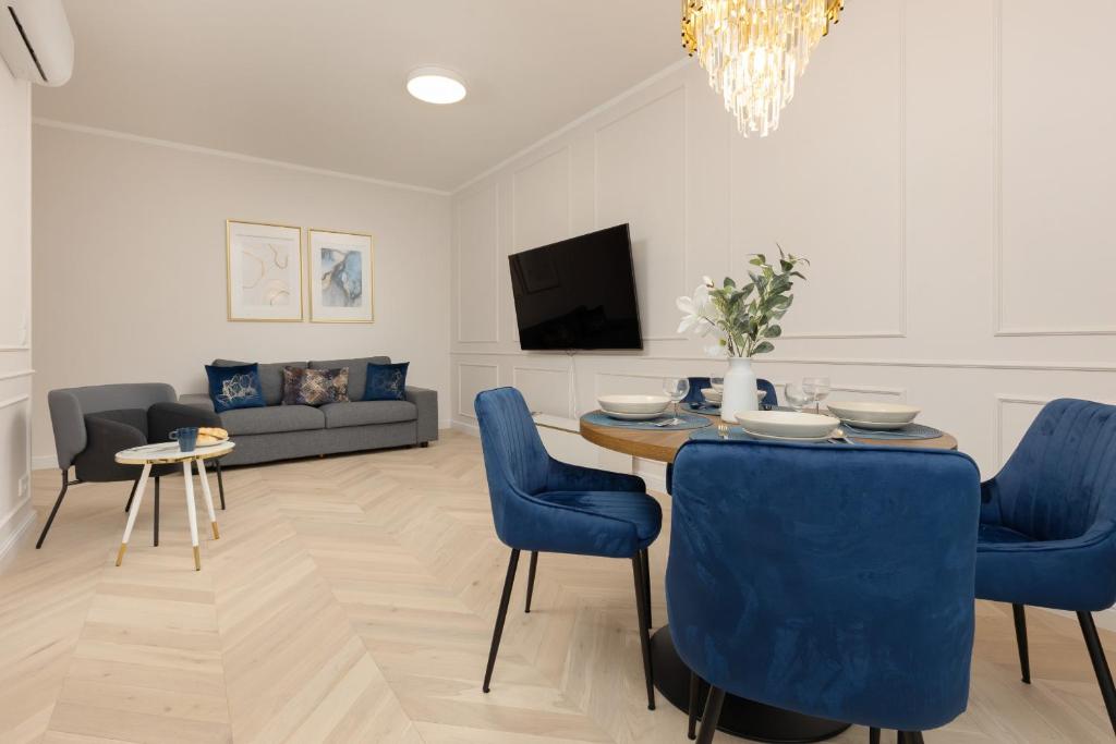 salon ze stołem i niebieskimi krzesłami w obiekcie Lux Apartment Niemcewicza with AC & Balcony Warsaw Ochota by Renters w Warszawie