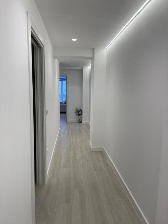 um corredor vazio com paredes brancas e pisos de madeira em Apartamento Arena Benidorm em Benidorm
