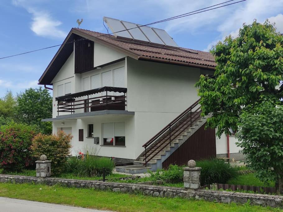 uma casa branca com uma escada em frente em Apartma Čampa em Kocevje