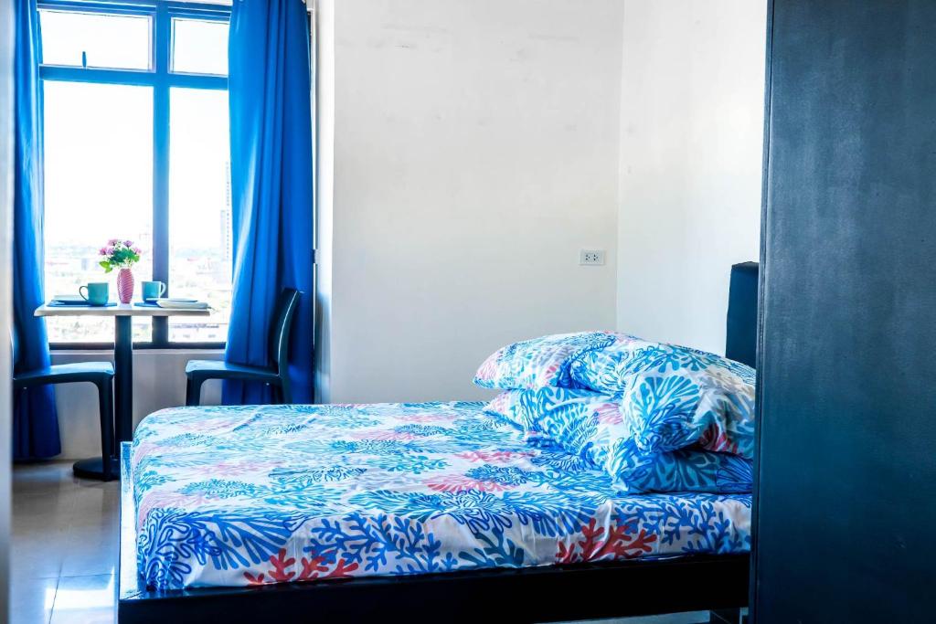 - une chambre avec un lit doté de draps bleus et une fenêtre dans l'établissement Mabolo Garden Flat, à Cebu