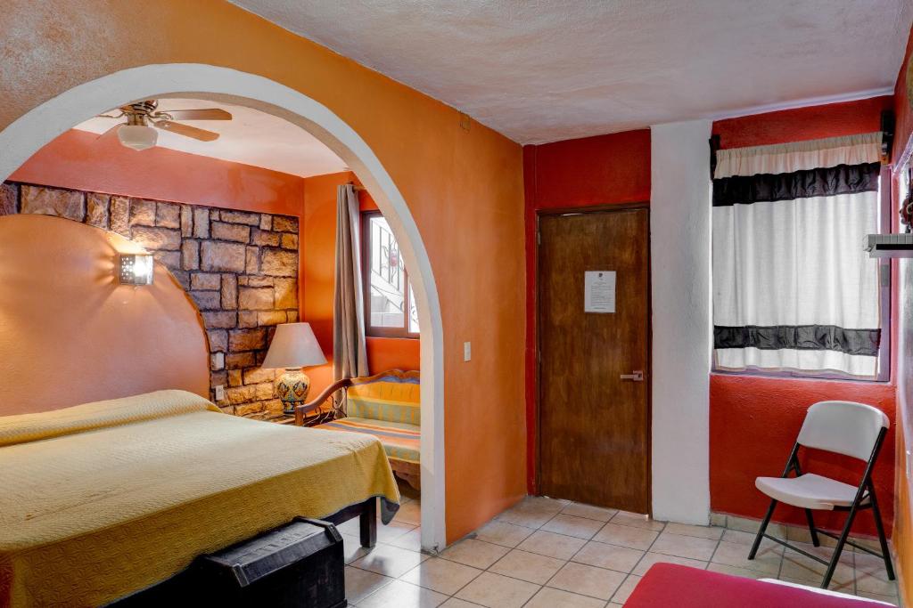 1 dormitorio con paredes de color naranja, 1 cama y puerta en Hotel Spa Casa del Sol, en Guanajuato
