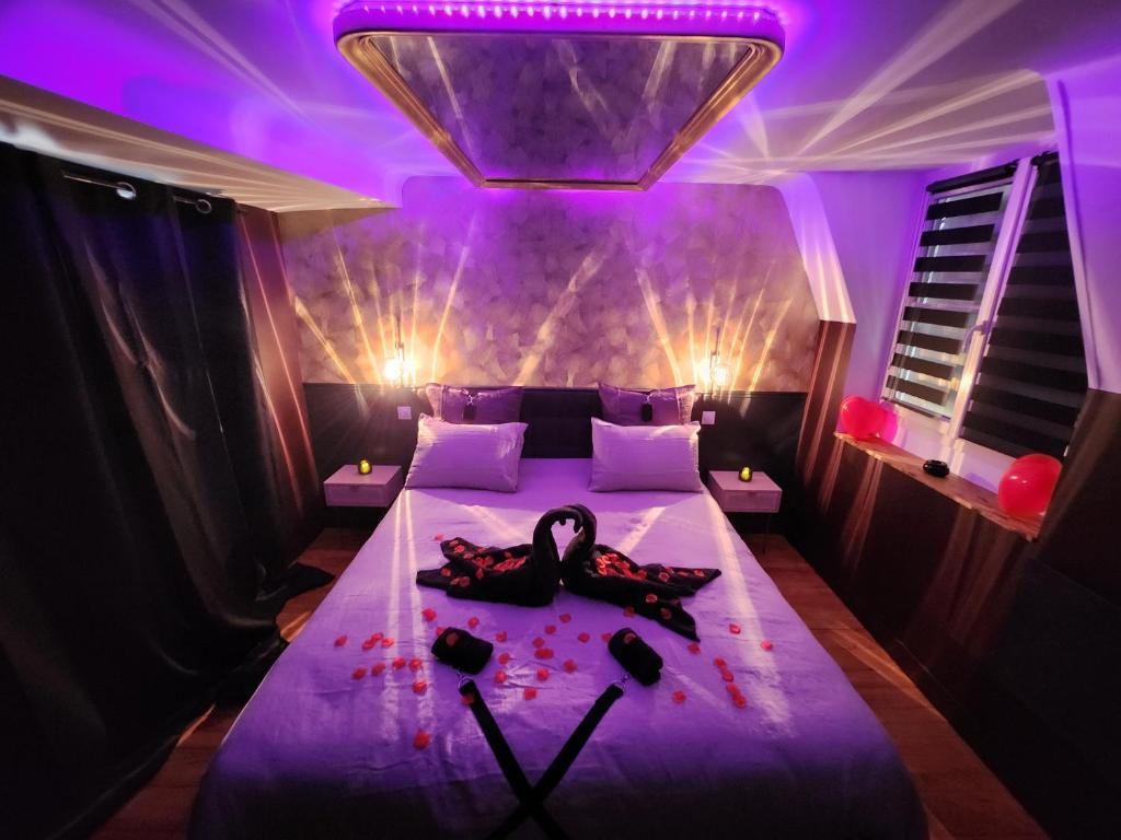 a woman laying on a bed in a room with purple lights at Caen, Tu m'aimes - Suite Romantique in Caen