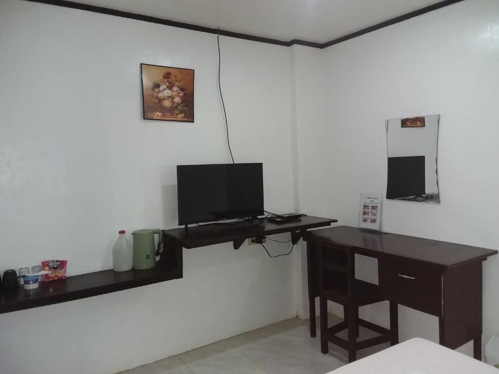 Zimmer mit einem Schreibtisch und einem Computer an der Wand in der Unterkunft Jupiters Garden Cottages in Lawa-an