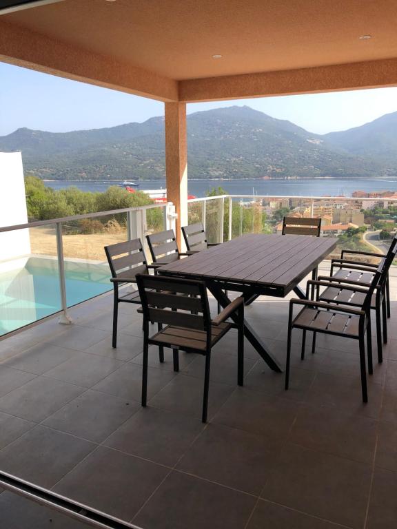 una mesa de madera y sillas en un balcón con vistas en Casa campa lumba en Propriano