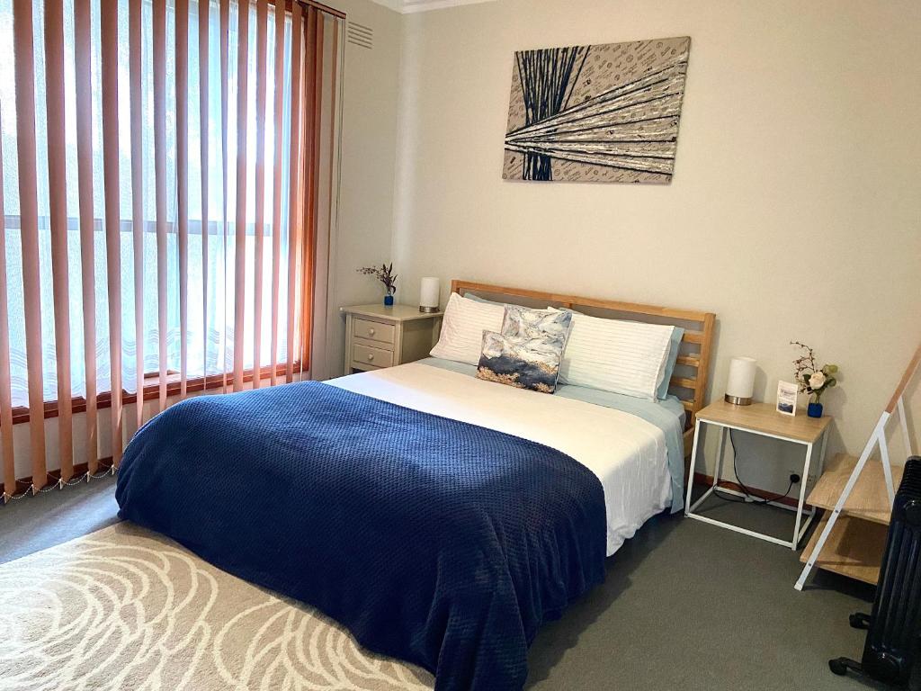 een slaapkamer met een bed met een blauwe deken bij BROOKS,BFast,WiFi,Nflx,Walk2Shop,Liquor,Food in Norlane