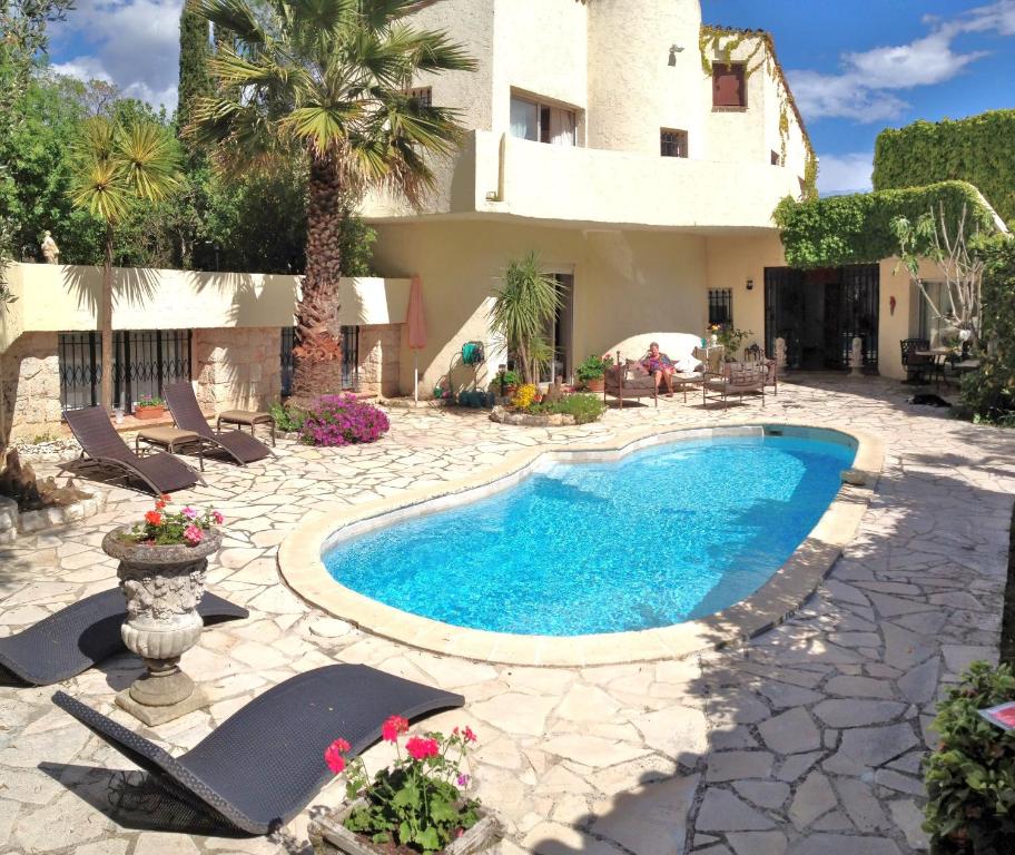 uma piscina em frente a uma casa com uma palmeira em Villla Ativoli em Vence