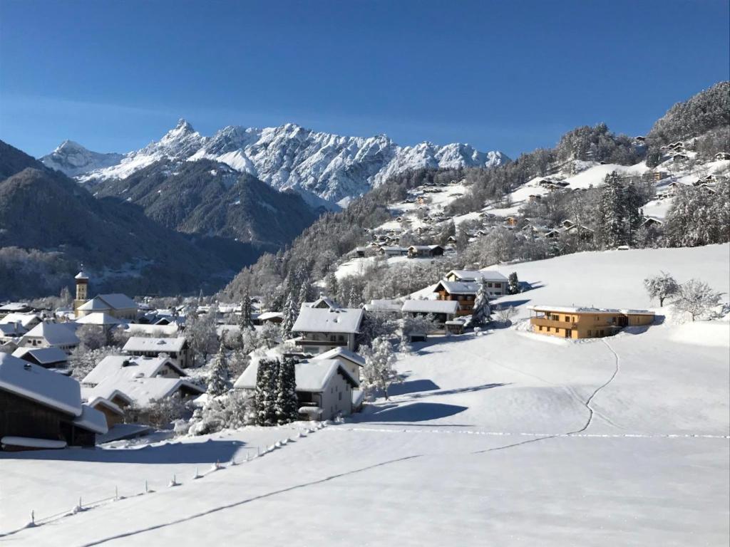 een dorp bedekt met sneeuw met bergen op de achtergrond bij Haus W in Schruns