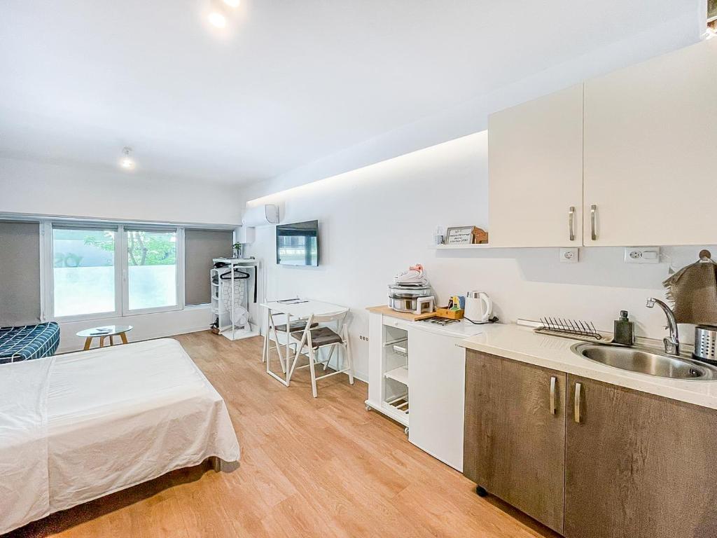 a kitchen with white cabinets and a bed in a room at Mini Suite Roman Agora in Thessaloniki