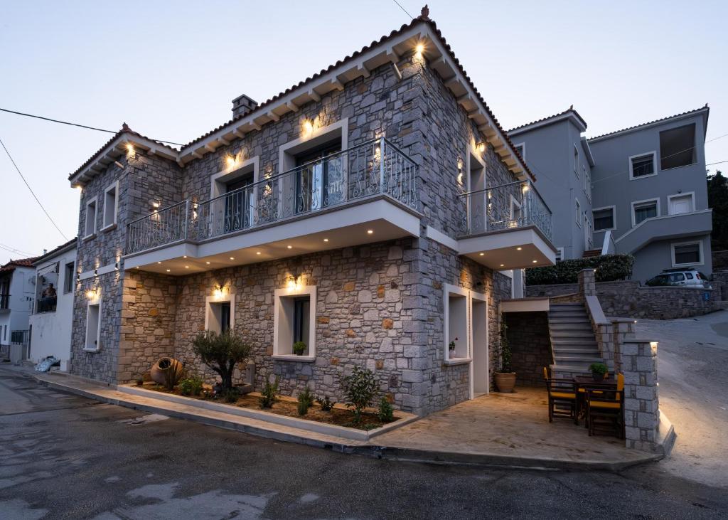 a stone house with a balcony and lights on it at Zeus & Emmanuil Luxury Houses in Myrina