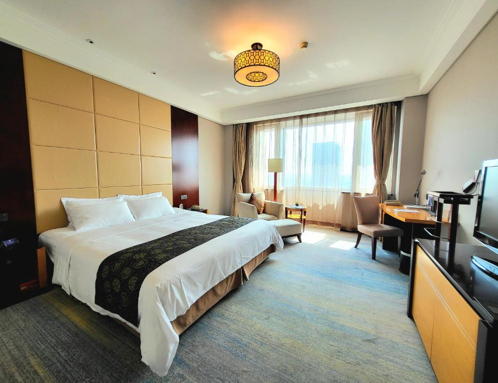 Pokój hotelowy z dużym łóżkiem i biurkiem w obiekcie Tianjin Saixiang Hotel w mieście Tiencin