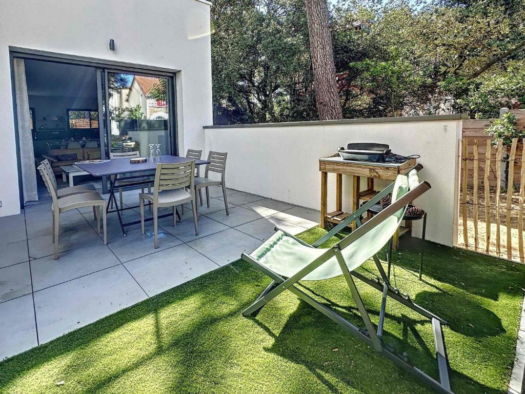 un patio avec une table et des chaises sur l'herbe dans l'établissement La Pinede 350m de la Plage, à Les Sables-dʼOlonne