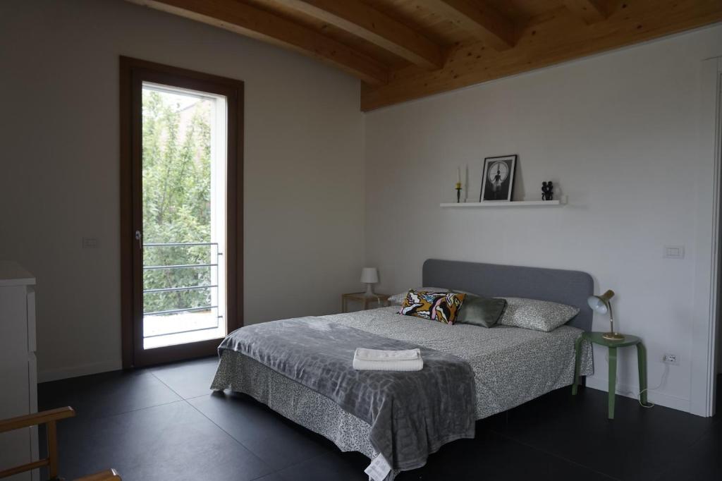 a bedroom with a bed and a large window at villa amarena, centralissima giardino e parcheggio in Angera