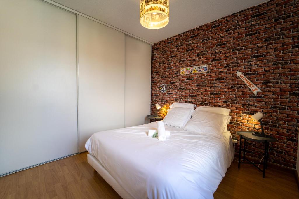 a bedroom with a brick wall and a white bed at appartement proche lac d'Annecy in Faverges