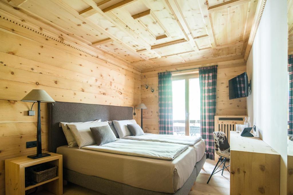 una camera con un grande letto in una stanza con pareti in legno di La Genzianella Bormio a Bormio