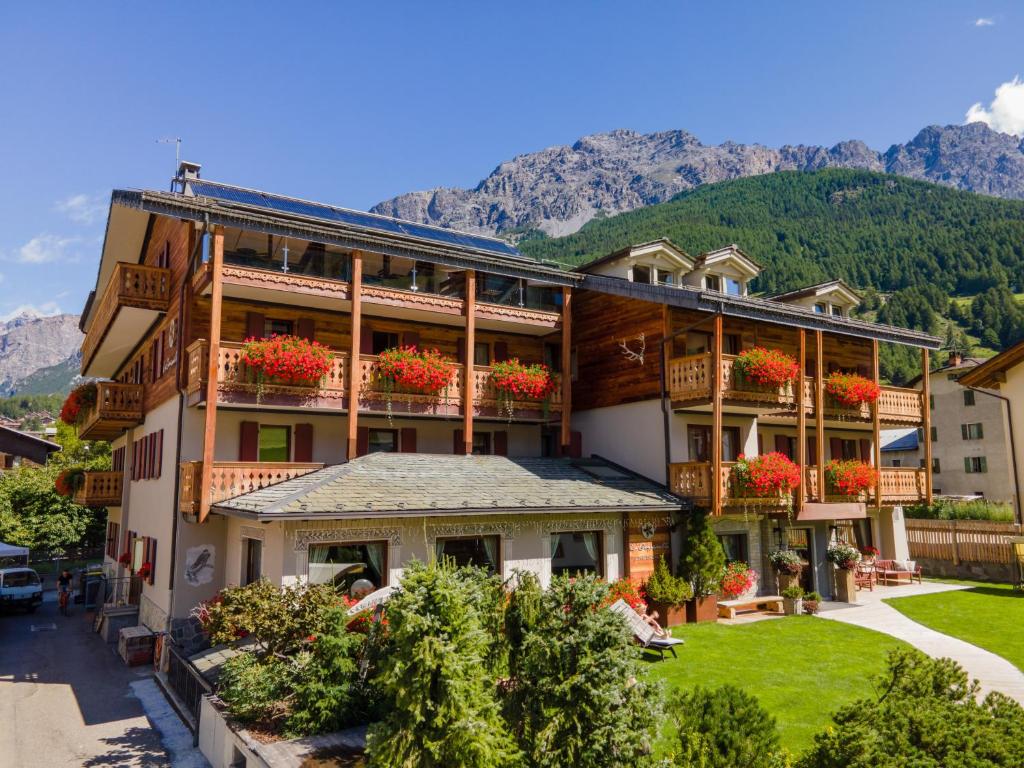 a building with flowers on the balconies with mountains in the background at La Genzianella Bormio in Bormio