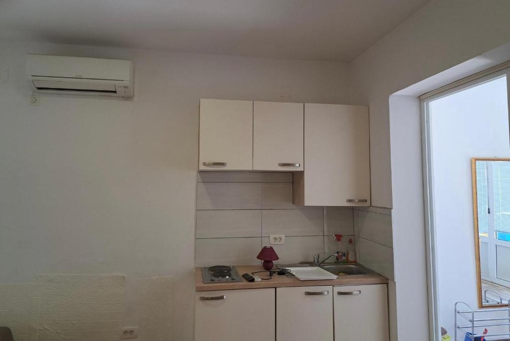 a small kitchen with white cabinets and a window at Villa Ika in Ploče