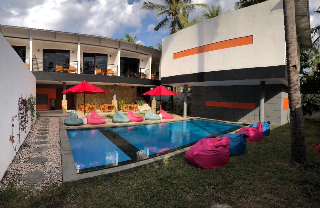 einen Pool mit bunten Stühlen und Sonnenschirmen neben einem Gebäude in der Unterkunft Soda Resort Gili Trawangan in Gili Trawangan