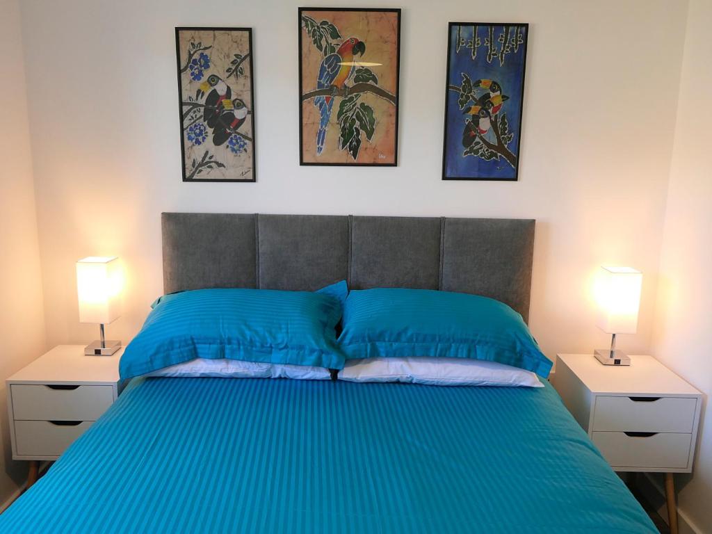 a bedroom with a blue bed with three pictures on the wall at Chez Ana in Saxmundham