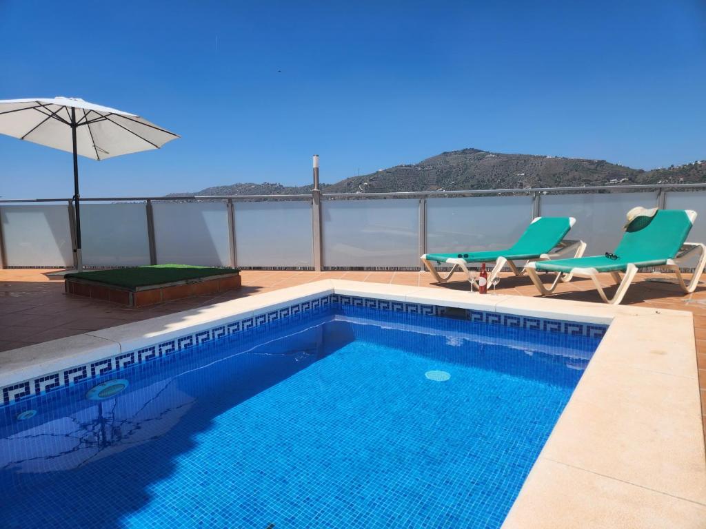einen Pool mit 2 Stühlen und einem Sonnenschirm in der Unterkunft Villa Esperanza - Canillas de Albaida in Canillas de Albaida