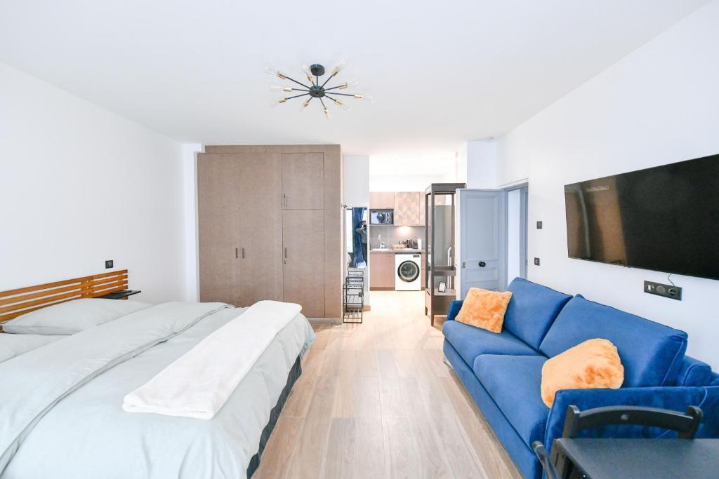 1 dormitorio con sofá azul y TV en Montmartre Charme et Élégance près du Sacré-Cœur, en París