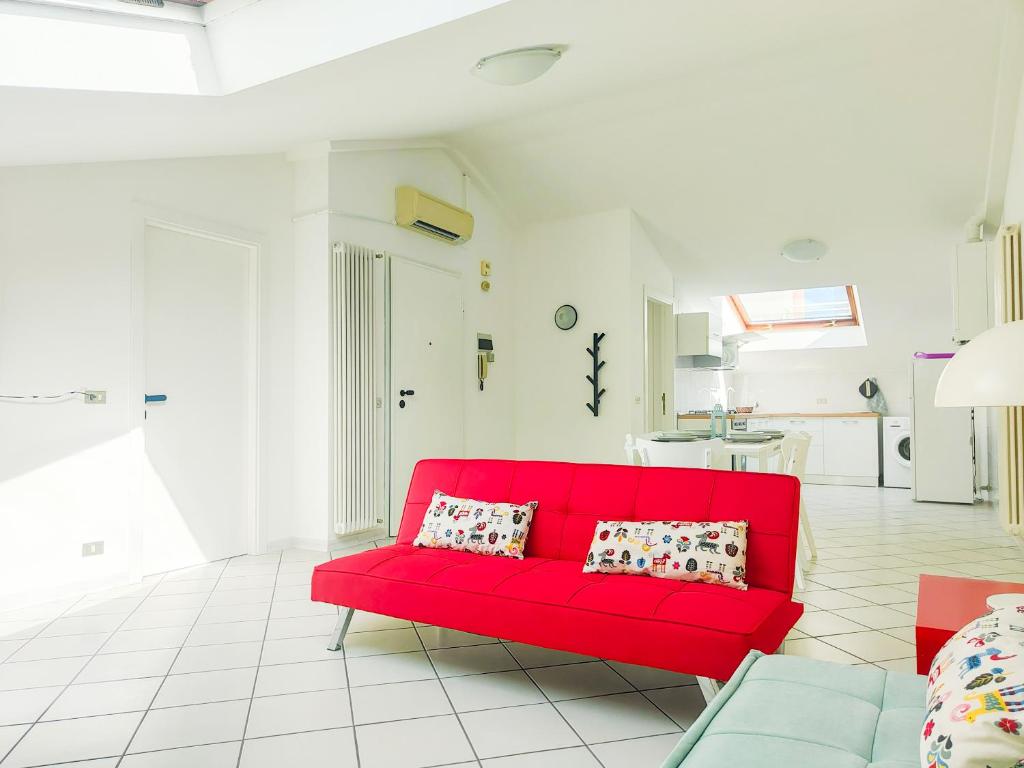 a red couch in a white living room at Homiday - BordoPineta Centro in Pineto