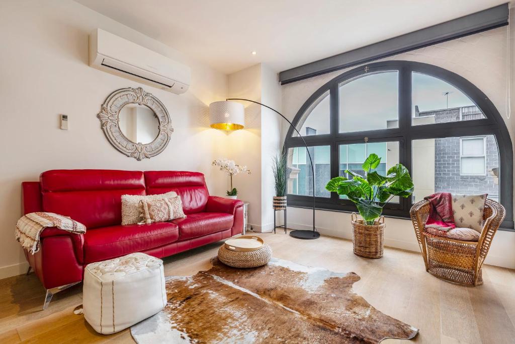 - un salon avec un canapé rouge et une grande fenêtre dans l'établissement Charming 1-Bedroom Heritage Apartment, à Melbourne