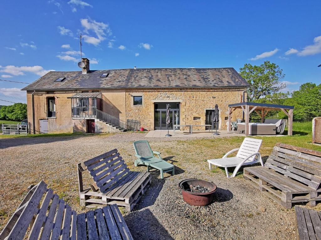 a house with two wooden benches and a fire pit at A l&#39;Orée du Lac, 500m lac de Chamboux in Saint-Martin-de-la-Mer