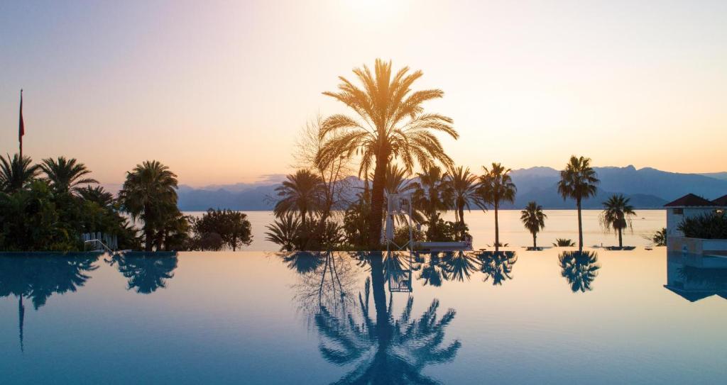een zwembad met palmbomen en de zonsondergang bij Akra Antalya in Antalya