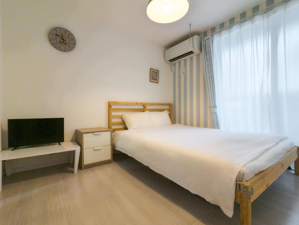 1 dormitorio con 1 cama, TV y reloj en japan house itabashi, en Tokio