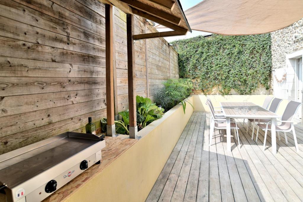 eine Terrasse mit einem Tisch und Stühlen sowie einer Holzwand in der Unterkunft La Paillotte - à 7min de la plage in Beaussais sur Mer