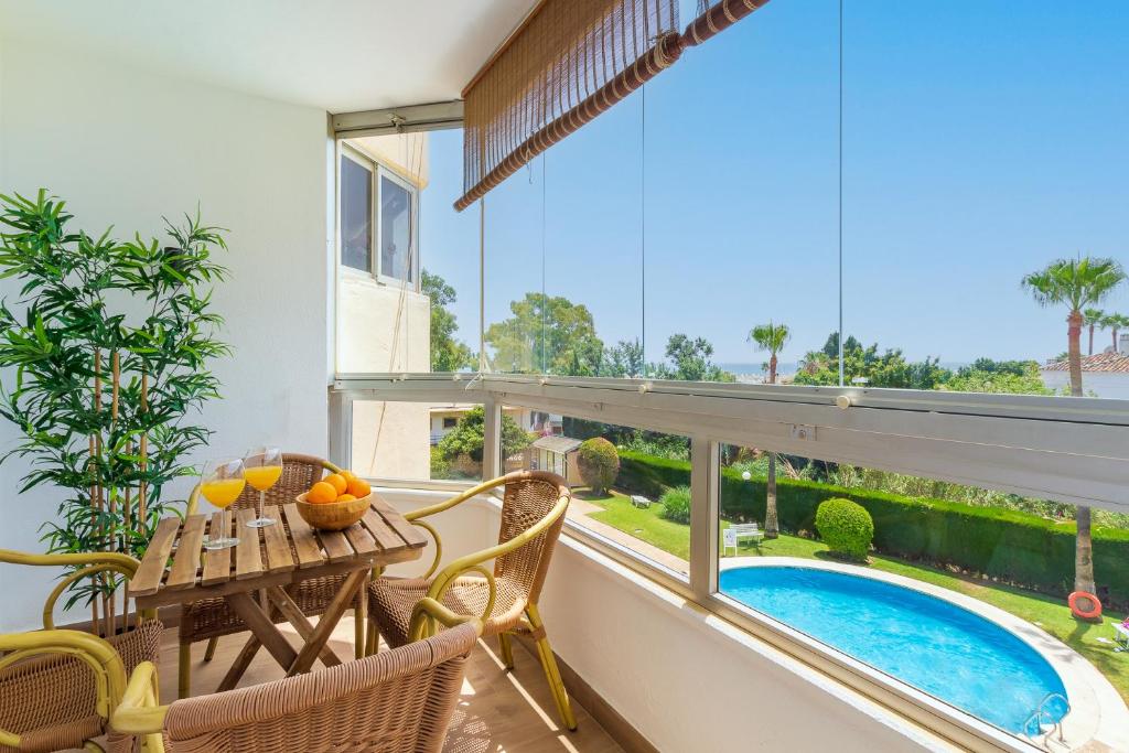 einen Balkon mit einem Tisch, Stühlen und einem Pool in der Unterkunft Vistamarina A309 By IVI Real Estate in Torremolinos